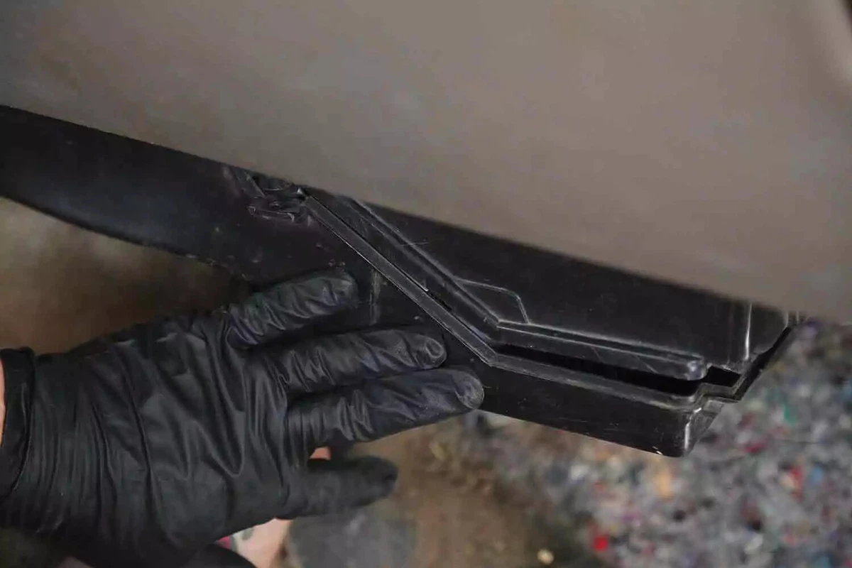A mechanic wearing a black glove replaces the cover on the HVAC box.