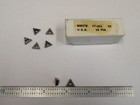 Seven metal TT-221 C2 carbide inserts with triangular black tips, shown beside labeled brown cardboard box.