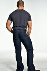 Man wearing dark denim men's bootcut jeans size 32x35 with back pockets and subtle rainbow-striped inner waistband.