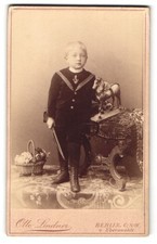 Fotografie Otto Lindner, Berlin, junger Knabe im Matrosenanzug mit Holzpferd au 