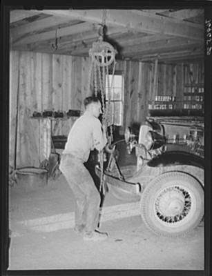 Garage owner hoisting car so that he can make repairs. Pie Town, New Mexico