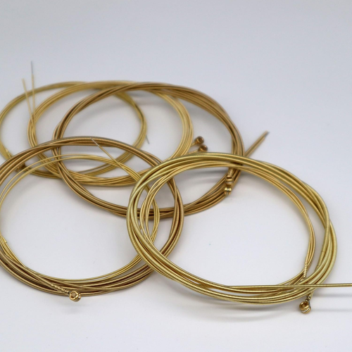 Gold-wound guitar strings with black ball ends on white background, arranged in clear plastic packaging.