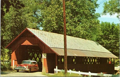 Old car driving through covered bridge in Brattleboro Vermont