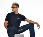 Black denim men with white script “Culture” text on chest, seated on gray box, size 32x35.