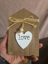 small, wood block sign with a white heart accent and the word "love" printed