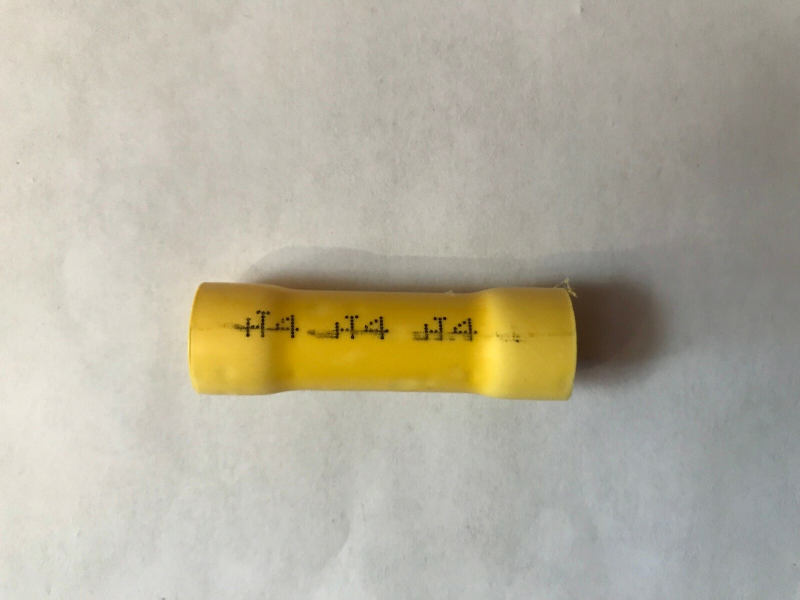 Yellow cylindrical Hillsdale 20626 vinyl 4-gauge butt connector with black printed specifications on a white surface.