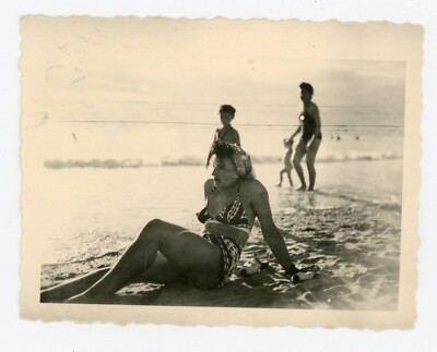 FOTO SNAPSHOT, die Profilfrau im Badeanzug am Strand sitzend