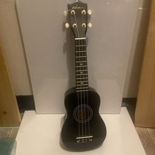 ukulele, the body and neck is black, out of tune I believe, white strings,  bag