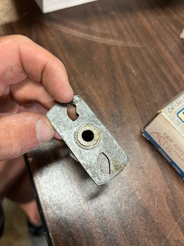 Close-up of worn silver metal 1964-1966 Ford truck distributor cam with two circular holes and visible metal wear marks.