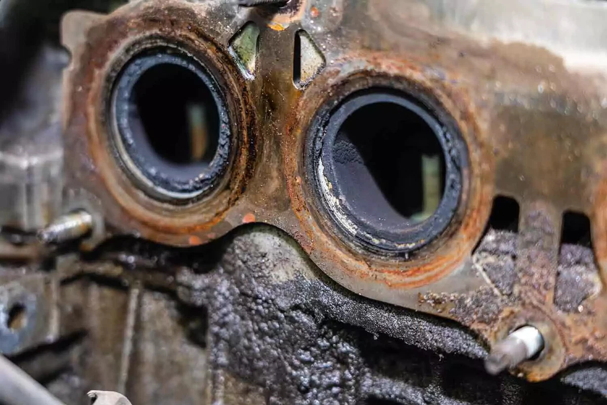 A close-up view of an old rusty metal exhaust manifold gasket.