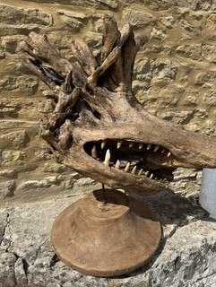 Wooden tree stump formed in to animal head with stone teeth