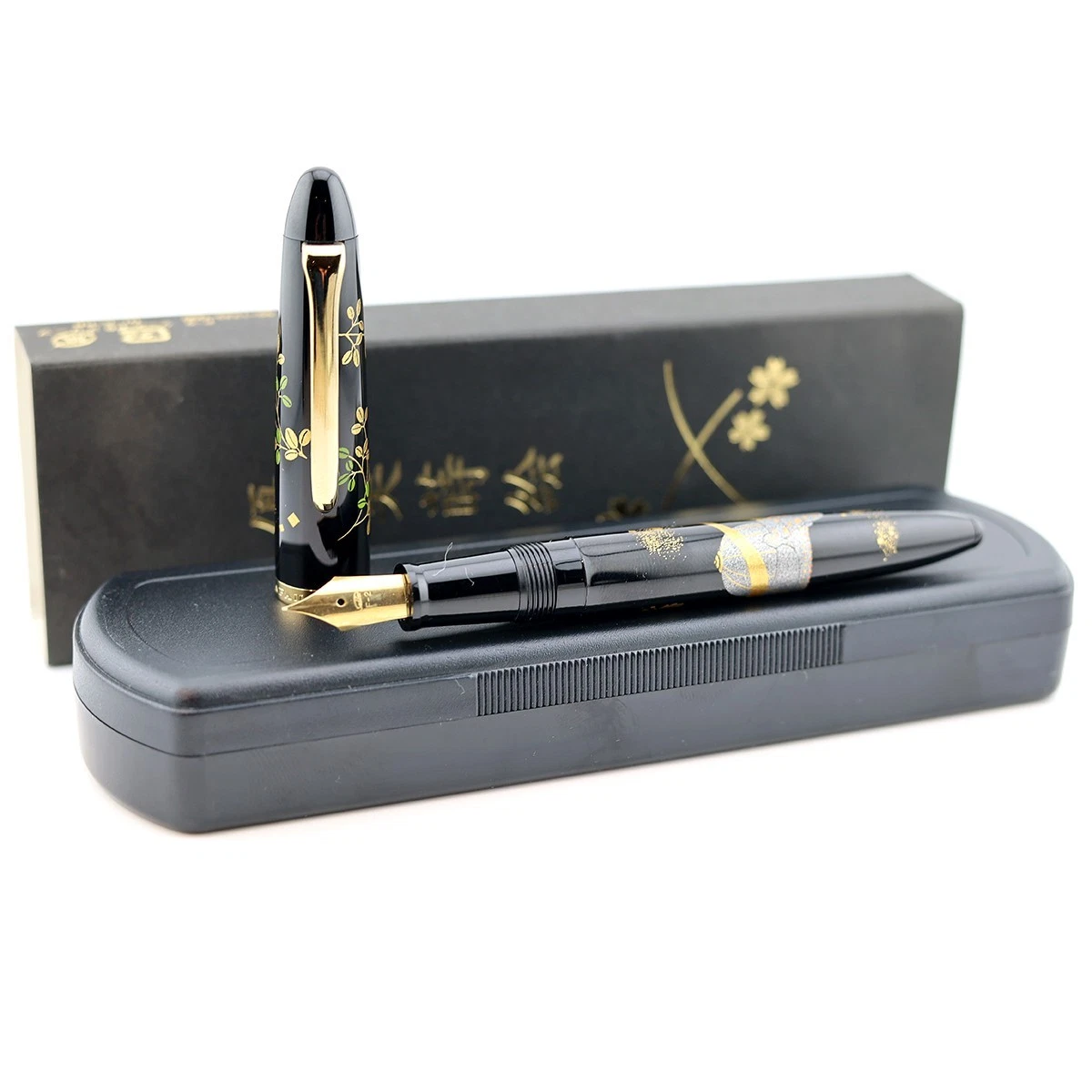 Black Sailor Maki-e fountain pen with gold floral and leaf design, displayed on purple box with Japanese text.