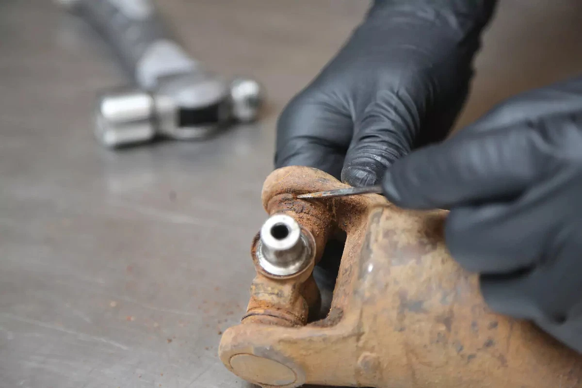 A mechanic wearing black gloves removes the inside clip from a driveshaft.