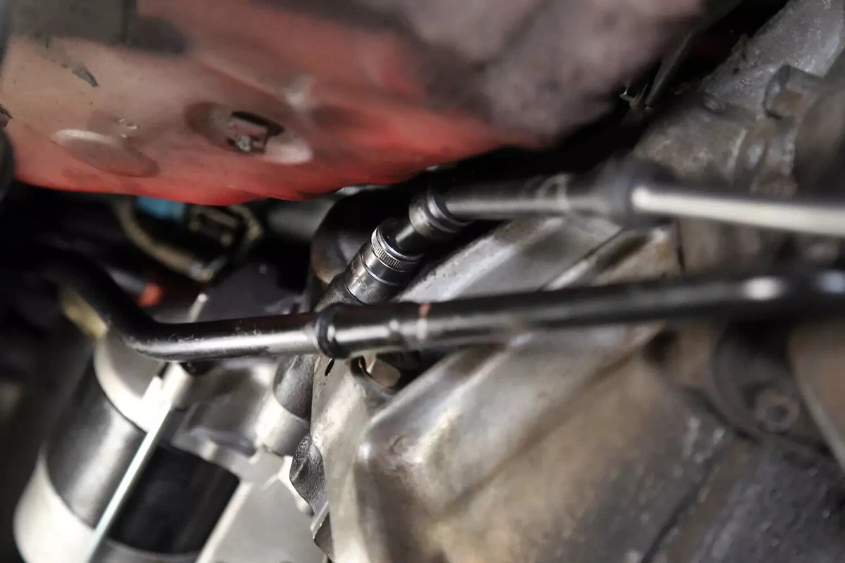 Tightening a bolt on the new starter with a socket wrench.
