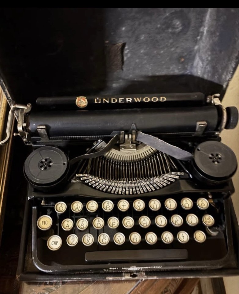 A 1920s Underwood portable in black steel with its original case — this is THE iconic typewriter of the Jazz Age, and it looks like a prop from a Hemingway biopic.