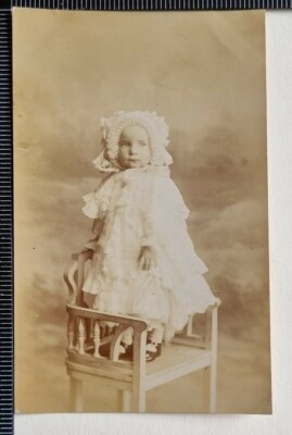 VINTAGE POSTCARD CHILD TODDLER STANDING ON CHAIR VERY FRILLY CLOTHES & HAT