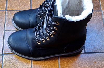 Es handelt sich um schwarze Winterstiefel mit weißem Kunstfellfutter und Schnürs