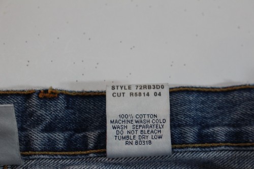 White fabric tag on blue jeans with yellow stitching, showing style 72RB30, cut R5814, and care instructions.