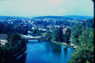RED BORDER SLIDE Blue river and bridge through a tree-lined city.