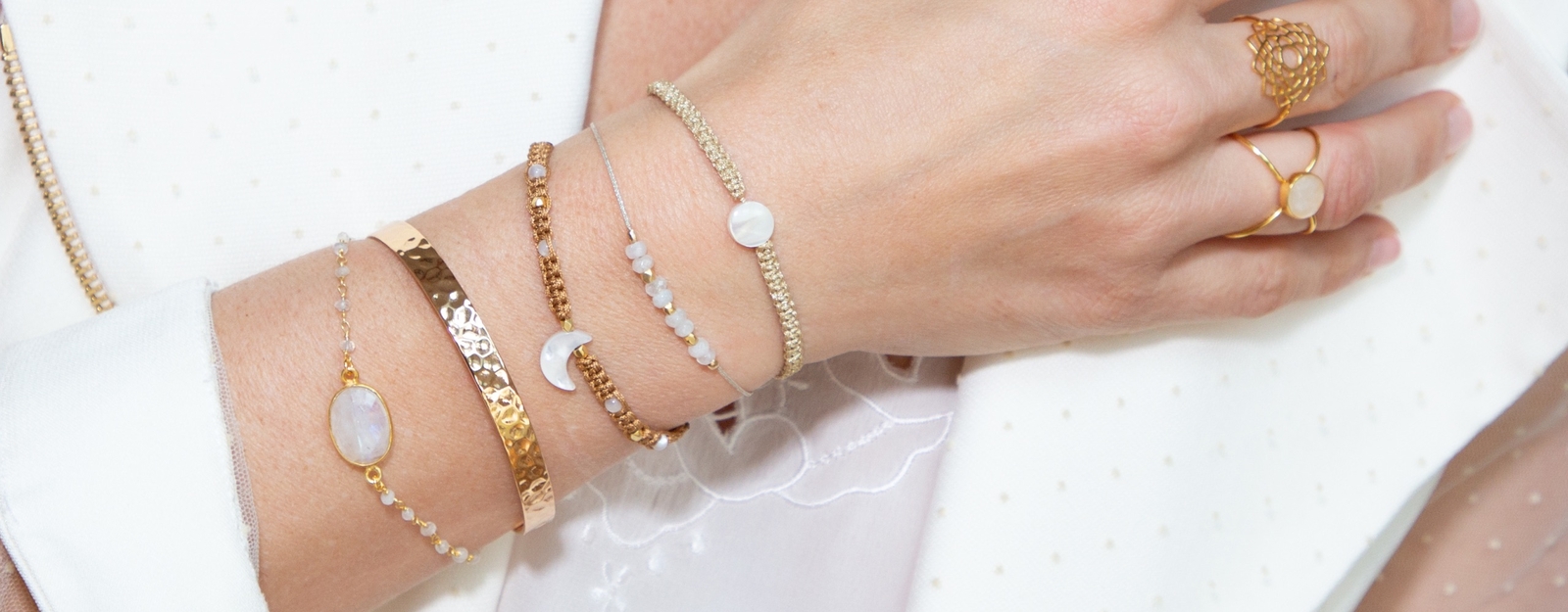 Elegante Hand mit mehreren filigranen Armbändern und goldenen Ringen, die schlichte und stilvolle Accessoires perfekt kombinieren.
