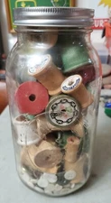 Vintage mixed colored wooden sewing thread spools & buttons in a large Ball jar 