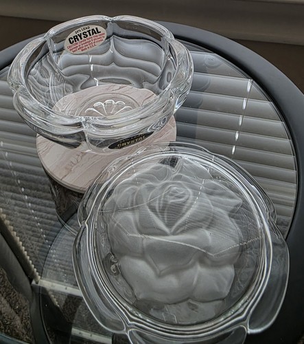 Clear vintage glass bowl with embossed rose design, matching lid, and “Crystal” logo on white base.