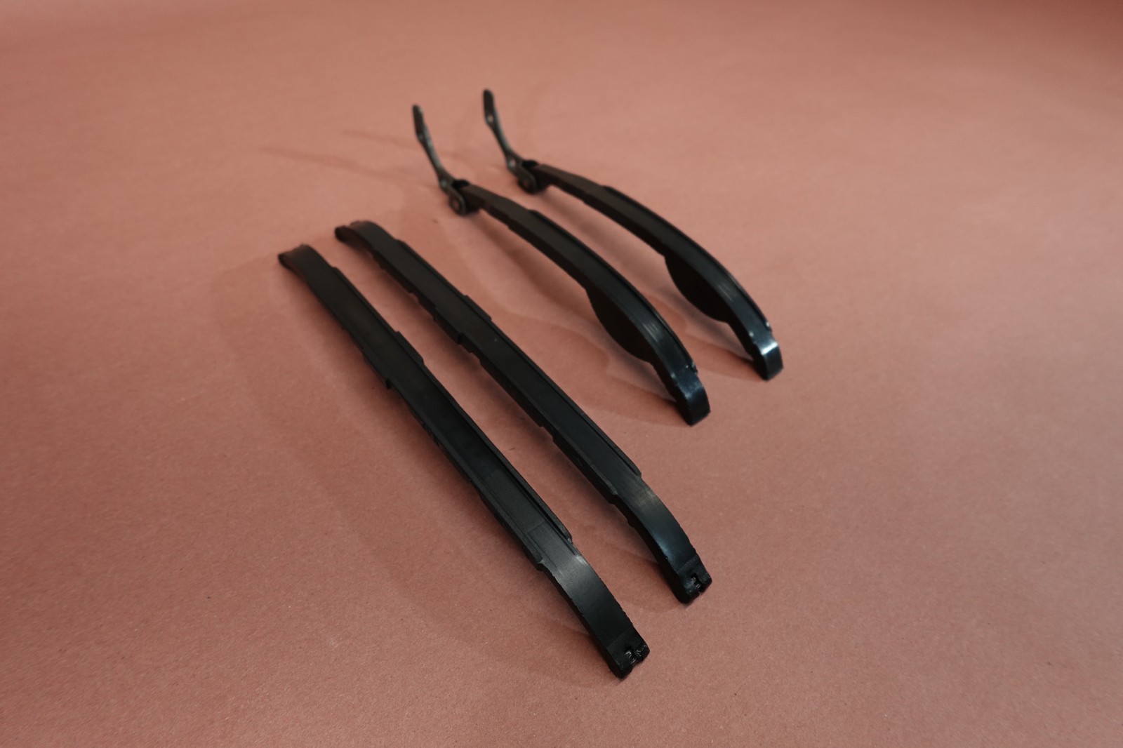 Black metal 1998-2015 Yamaha VStar V Star 650 XVS650 cam shaft timing chain guides on a brown surface.