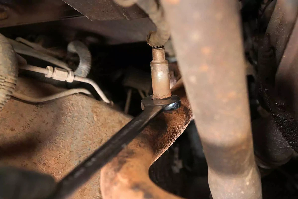 An open-end wrench loosening the oxygen sensor from its bung.