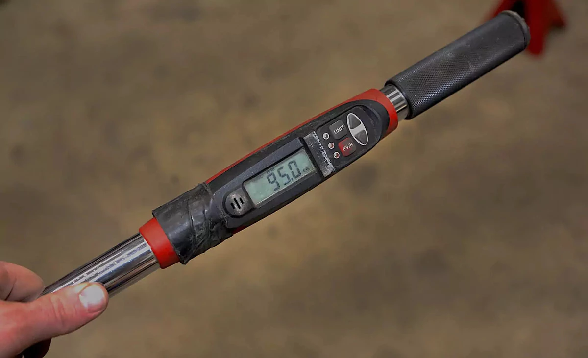 A mechanic adjusts a torque wrench to a setting of 95 pound-feet.