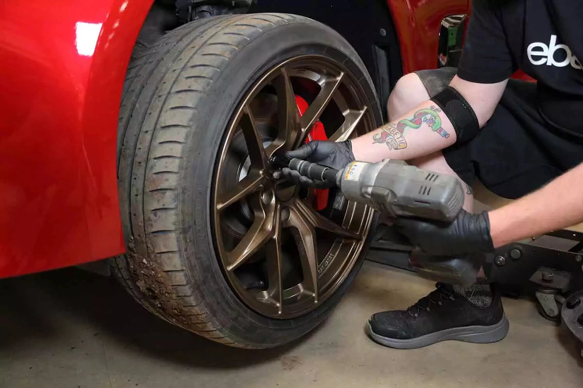A mechanic uses an impact wrench to remove a wheel from the vehicle.