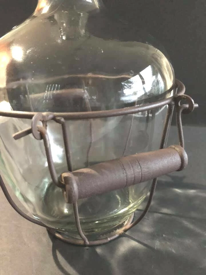 Botella gruesa de vidrio transparente con asa de estante de metal rústico Foto 3 de 4