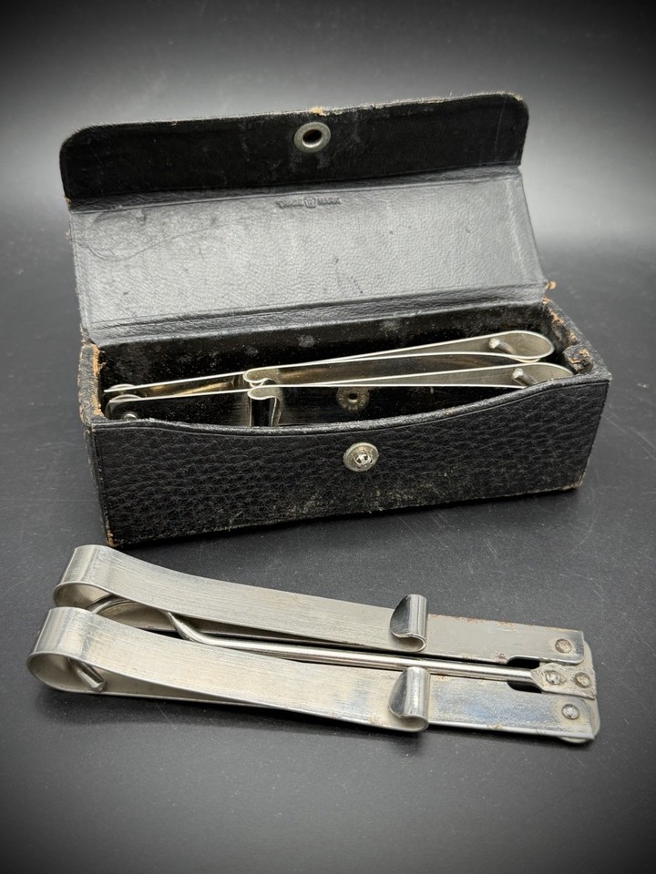 A vintage folding metal travel hanger set in its original case — a genuinely clever mid-century travel relic that's practical, retro, and prop-perfect.