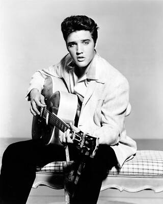 Elvis Presley in casual shirt and jacket seated with guitar