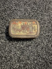 Antique decorative tin with horse-drawn carriage scene.