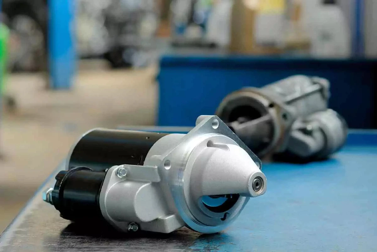 Two starters, sitting on a workbench. The starter in the foreground is new. It will replace the old starter in the background.
