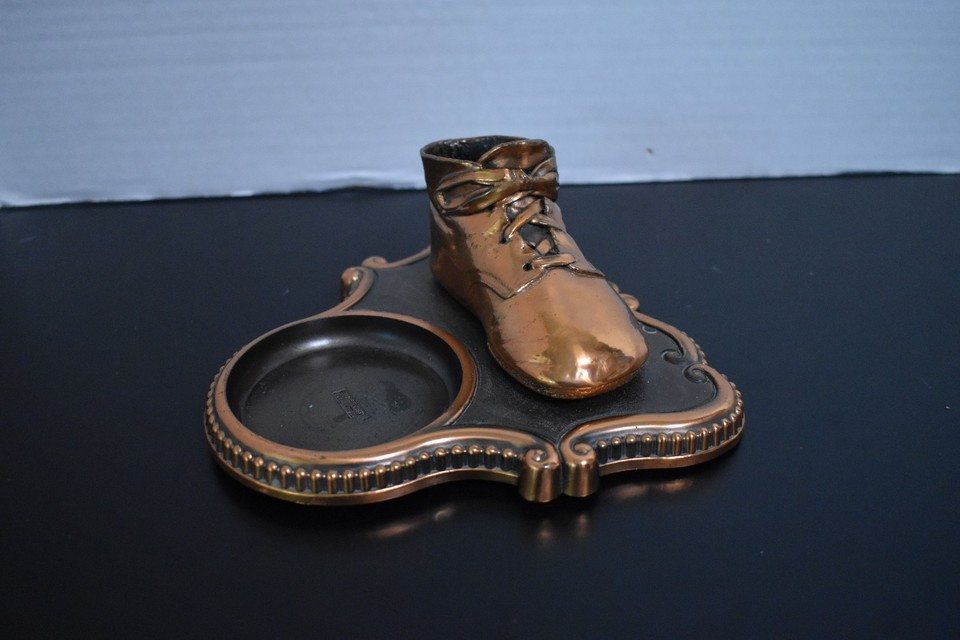 A bronzed baby shoe repurposed as a desk accessory with a coin dish — utterly weird, utterly charming, and completely impossible to find anywhere else.