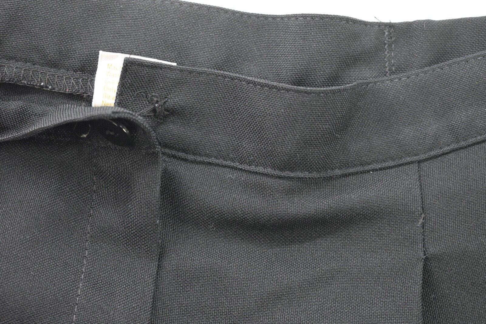 Black Jantzen women’s pants with front button closure, pleated detailing, and white size 12 tag on waistband.
