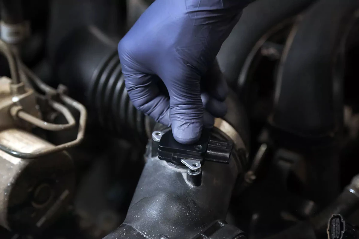 A mechanic presses on an MAF sensor.
