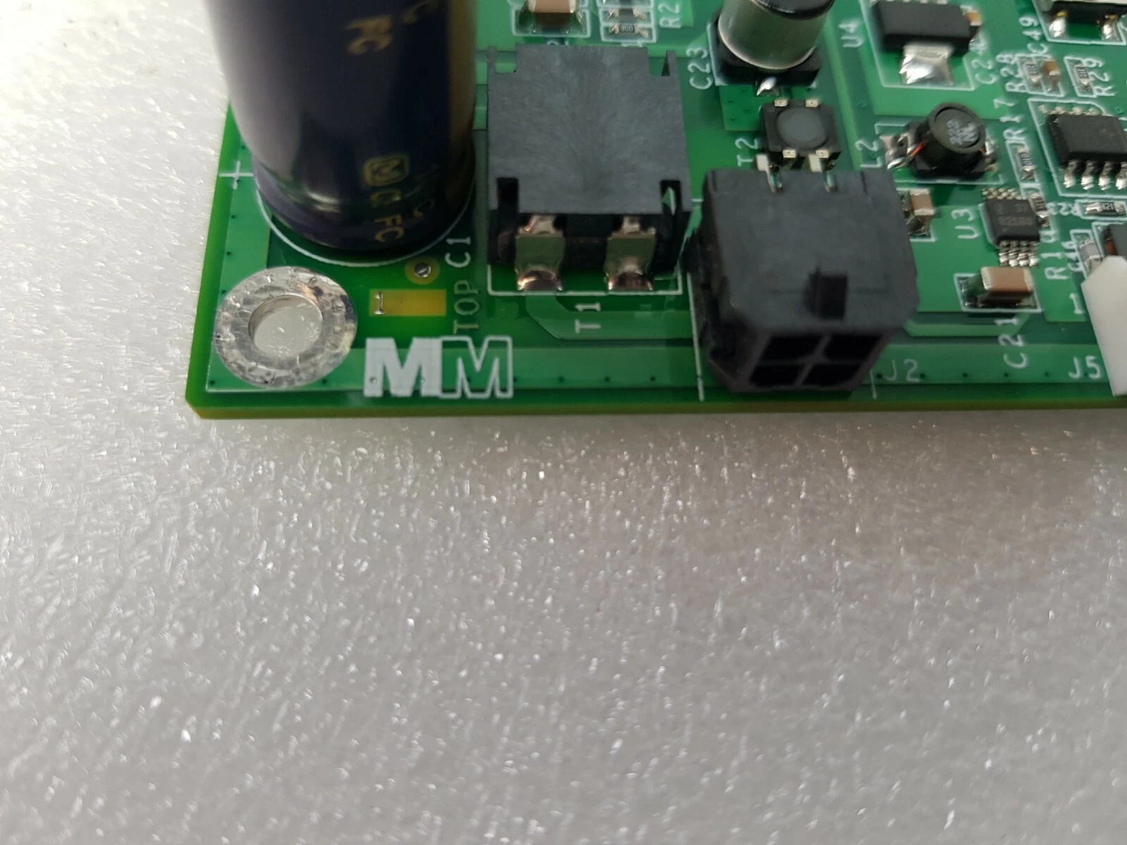 Corner of the EA-10000481 board with MM logo, power connector and capacitors