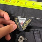 Black faded bootcut jeans with white stitching, button closure, and “Lucky Brand Made in America” tag with red Y2K grunge aesthetic.