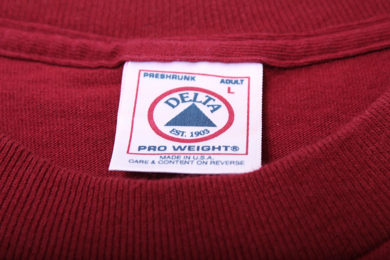Red vintage 1990s shirt with white embroidered Delta logo, “Made in U.S.A.” text, and care instructions on label.