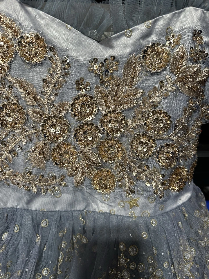 Vestido niña flor tul gris claro con lentejuelas doradas y adornos estrella. Foto 3 de 4
