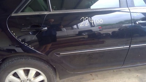 Black side door of 2002-2006 Camry with white handwritten text “224100” and “white” wheels.
