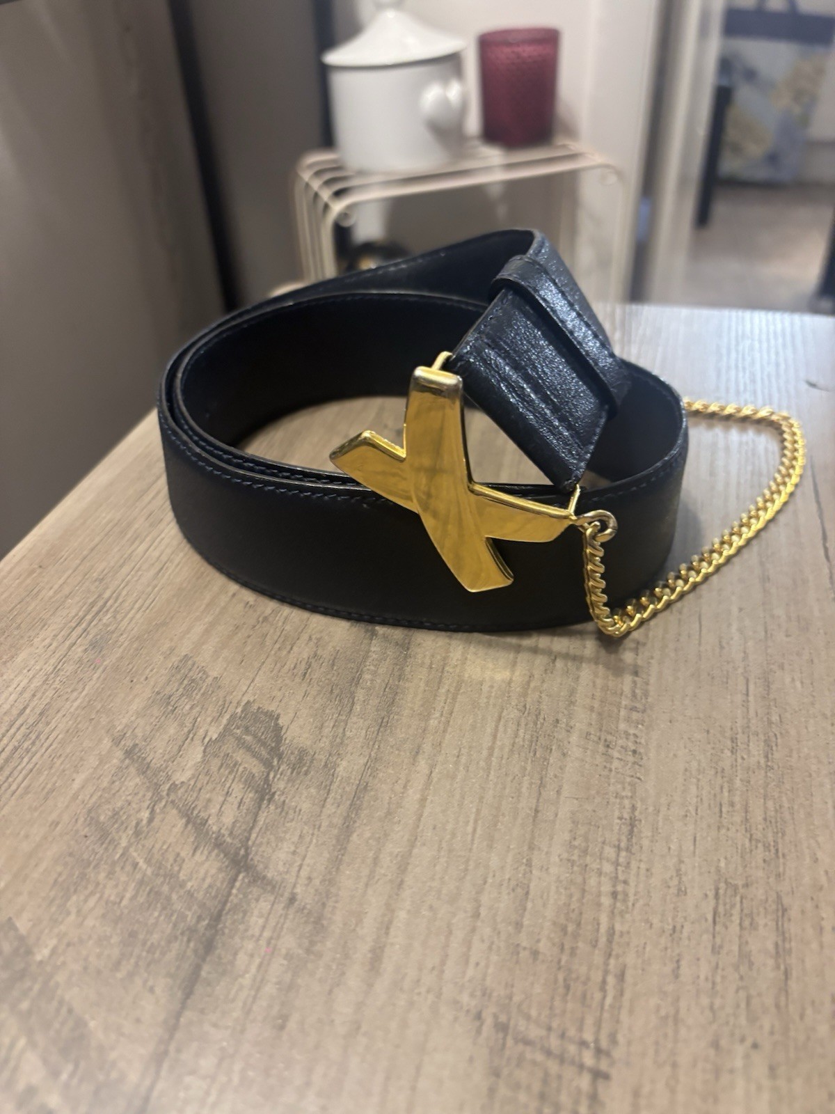 A black leather Paloma Picasso belt with a gold-tone kiss-motif buckle, made in Italy.