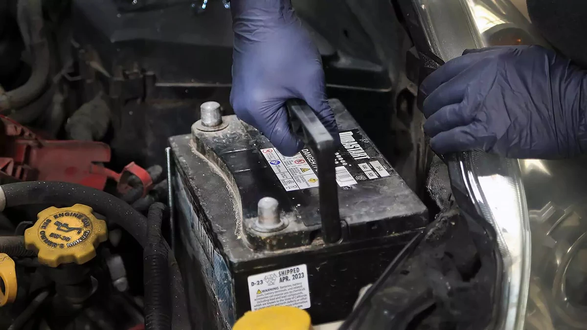 Removing a used car battery as part of a DIY battery replacement.
