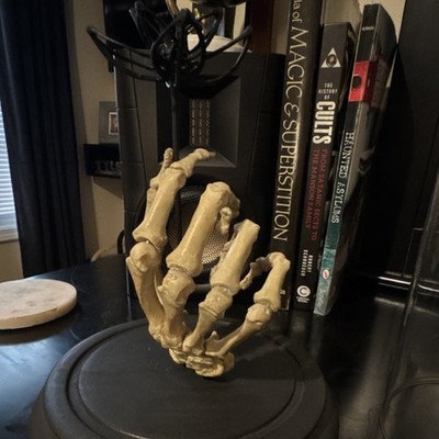 Human skeleton hand holding a bespoke bone flower.