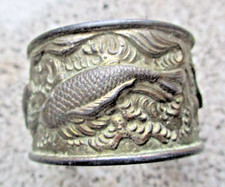 Pierścionek z serwetką cyny z rybą na nim.