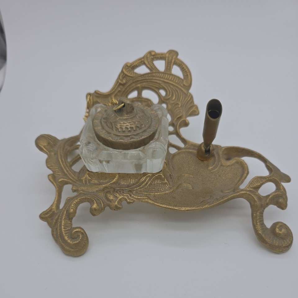 A complete ornate brass inkwell set with glass insert and pen holder — a self-contained antique writing station that looks incredible on any desk.