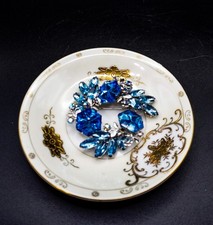 Vintage blue rhinestone floral wreath brooch with silver-tone metal.