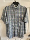 Men’s long-sleeve button-up shirt with green, blue, and yellow plaid pattern and chest pocket, hanging on black hanger.
